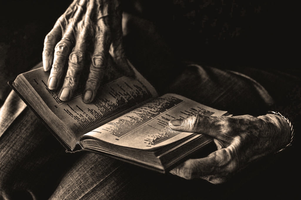 Fotografía virada al blanco y negro con tonalidades sepia.
En ella se ve, centradas en un primer plano, unas manos, de una persona muy anciana, hojeando un libro.
Nada más y nada menos.